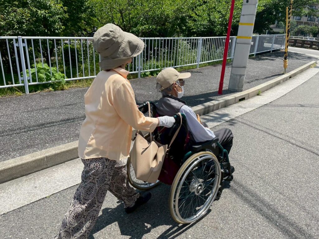 車椅子に乗った高齢者を押す介護スタッフ